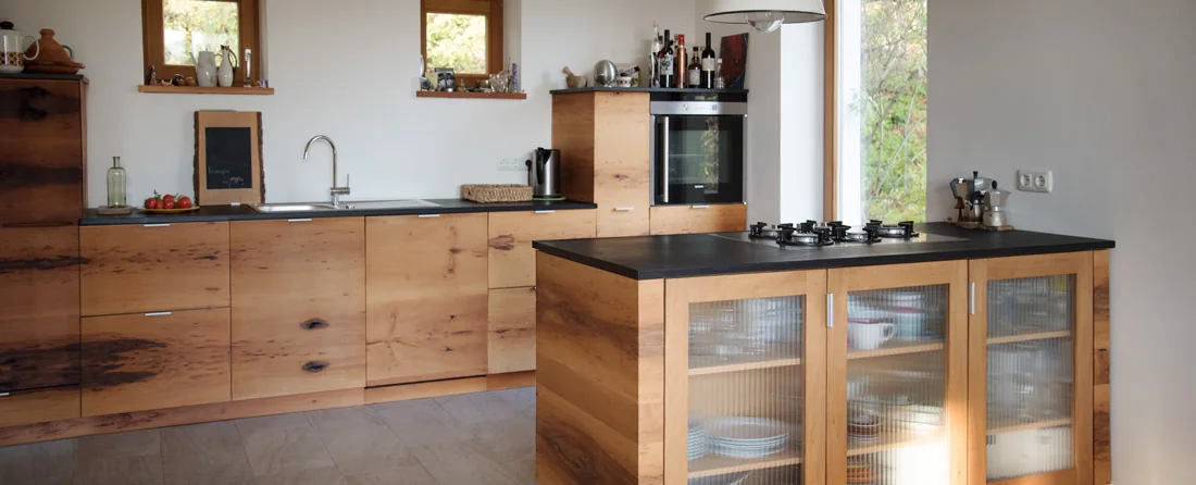 Helle Küche mit individuell gefertigten Holzmöbeln und dunklen Arbeitsplatten